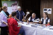 Johann Schneider-Ammann (2.v.r.) bei signieren der Fotobücher mit Natascha Mächler, Leiterin Reitstall Rathausen. (Bild: PD/Nique Nager)