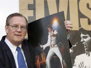 Der Elvis-Fotograf Ed Bonja posiert am 13. Aug. 2007 in Berlin mit einem Foto des «King of Rock 'n' Roll» vor einem Ausstellungsplakat. Im September 2019 ist Bonja im Alter von 74 Jahren gestorben. (Bild: Keystone/AP/MICHAEL SOHN)