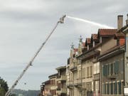 Ein Feuerwehrmann bekämpft von einer Drehleiter aus den Dachstockbrand. (Bild: Kantonspolizei Freiburg)