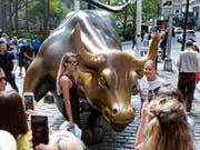 Der bronzene Bulle wurde von einem Mann beschädigt. Das hält die Menschen aber nicht davon ab, sich mit ihm fotografieren zu lassen. (Bild: KEYSTONE/FR61802 AP/CRAIG RUTTLE)