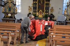 Der aufklappbare Kran wird durch die engen Kirchenbänke geschoben.