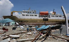 Ein Schiff ist mit dem Tsunami an Land gestrandet. (AP Photo/Tatan Syuflana)
