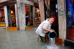Diese Frau schöpft Wasser aus einem überfluteten Laden. (Bild: Andrea Merola/Keystone (29. Oktober 2018))