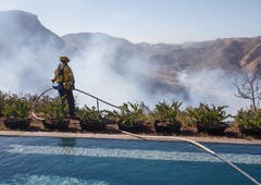 Ein Feuerwehrmann überwacht das Hinterland eines vom Feuer verschonten Hauses. (Bild: Eugene Garcia (West Hills, 11. November 2018))