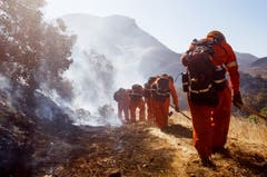 Feuerwehrmänner beim Ersticken von Glutherden und mähen von Brandschneisen im Hügelland im westlichen Kalifornien. (Bild: Eugene Garcia, 11. November 2018)