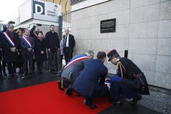 Der französische Premierminister Edouard Philippe (Mitte) und der Bürgermeister des Pariser Vororts Saint-Denis, Laurent Russier (links mit Trikolore-Band) legen vor der Gedenktafel beim Stade de France Blumen nieder. (Bild: Yoan Valat/EPA (Paris, 13. November 2018))