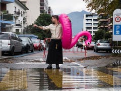 Ein Kellner der Lungolago-Pizzeria watet mit einem rosa Flamingo über die überschwemmte Strasse in Locarno. (Bild: KEYSTONE/TI-PRESS/ALESSANDRO CRINARI)