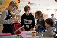 Zukunftstag an der Schule Unterlöchli in Luzern. Im Bild links Nando und (in der Mitte in schwarz) Janis erklären den Schüler, wie man eine Brücke aus Papier baut. Bild: Corinne Glanzmann (Luzern, 08. November 2018)