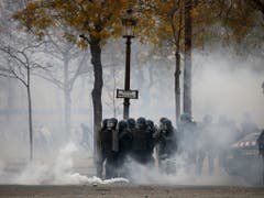 Tränengaseinsatz der Polizei auf den auf den Champs-Elysées in Paris als Aktivisten der «Gelbwesten»-Bewegung bei neuen Protesten eine Sperre durchbrechen wollten. (Bild: KEYSTONE/AP/KAMIL ZIHNIOGLU)