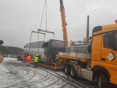 Der Kran lädt den Unglücksbus auf einen Tieflader. (Bild: Monika Freund, Keystone-SDA)