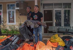 Ein Mann hält ein Kind, dass bei der Tsunami-Katastrophe ums Leben gekommen ist. (Bild: Fauzy Chaniago/AP (Carita, 23. Dezember 2018))