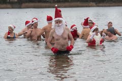 Mitglieder des Schwimmklubs «Berlin Seals» tragen für ihr traditionelles Weihnachtsschwimmen im Orankesee Weihnachtsmützen und Nikolausbärte. (Bild: Paul Zinken/AP (Berlin, 25. Dezember 2018))