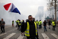 Ein Demonstrant schwingt die französische Tricolore auf der Avenue des Champs-Élysées. (Bild: Rafael Yaghobzadeh/AP Photo (Paris, 08.12.2018))