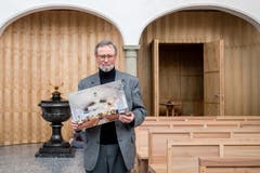 Hansruedi Kleiber, leitender Priester Peterskapelle, in der renovierten Peterskapelle. Er trägt ein Bild von der Kirche vor ihrer Sanierung. (Bild: Philipp Schmidli, 7. Dezember 2018)