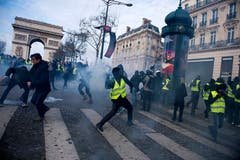 Die Gelbwesten kämpfen gegen die Polizeikräfte. Hier schleudert ein Demonstrant ein rauchendes Objekt. (Bild: Julien de Rosa/EPA (Paris, 08.12.2018))