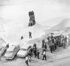 Autofahrer machen bei noch winterlichen Verhältnissen am 26. Mai 1963 einen Halt auf der Passhöhe am Gotthardpass und versorgen sich bei einem Kiosk-Häuschen unterhalb des Fliegerdenkmals für den seinerzeit hier abgestürzten Waadtländer Fliegeroberleutnant Adrien Guex. (Bild: Keystone)