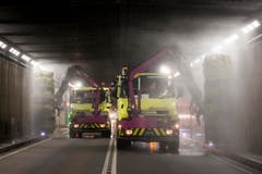Zwei Lastwagen putzen die Wände im Gotthard-Strassentunnel. (Bild: Keystone / Alexandra Wey)