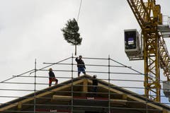 Im Beisein der beteiligten Handwerker wurde am Freitag im Rahmen des Richtfests der Richtbaum auf den Giebel gehievt. (Bild: Keystone)