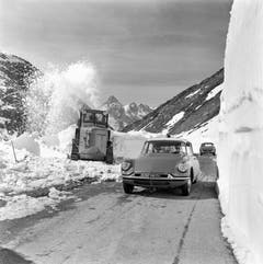 Schneeräumung auf dem Simplonpass, aufgenommen im April 1960. Ein Auto der Marke Citroen DS passiert eine Schneeschleuder. (Bild: Keystone)
