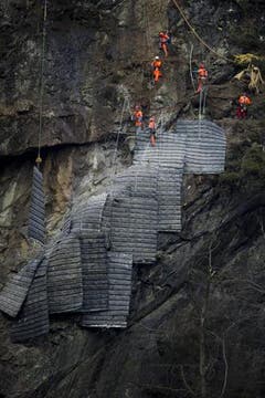 Die Schutzmatten für die Felssprengung über der Gotthard-Eisenbahnstrecke wurden bei Gurtnellen vom Helikopter an den Fels geflogen und von Spezialisten verlegt. (Bild: Keystone)