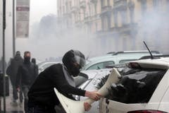 Ausnahmezustand in Mailand: Ein Aktivist schlägt mit einem Gegenstand die Scheibe eines parkierten Autos ein. (Bild: MASSIMO PERCOSSI)