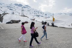 Die ersten Touristen spazieren neben den Schneemassen auf dem am 13. Mai eröffneten Gotthardpass. (Bild: DAVIDE AGOSTA)