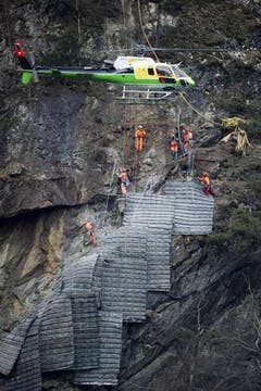 Die Schutzmatten für die Felssprengung über der Gotthard-Eisenbahnstrecke wurden bei Gurtnellen vom Helikopter an den Fels geflogen und von Spezialisten verlegt. (Bild: Keystone)