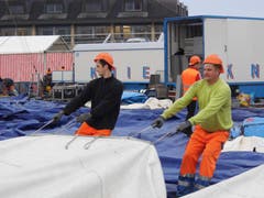 Harte Arbeit für ein kurzes Gastspiel: Arbeiter legen die riesigen Zeltplanen aus. (Bild: Martin Mühlebach / Neue ZZ)