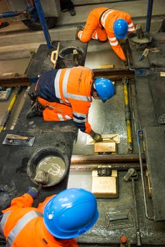 Arbeiter reiben mit einem goldigen Brett die Beton Schicht im längsten Eisenbahntunnel der Welt glatt. (Bild: SIGI TISCHLER)