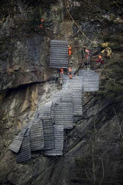 Die Schutzmatten für die Felssprengung über der Gotthard-Eisenbahnstrecke wurden bei Gurtnellen vom Helikopter an den Fels geflogen und von Spezialisten verlegt. (Bild: Keystone)