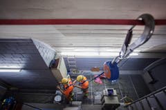 Zwei Arbeiter sichern sich während des Abtransports eines Lüftrades der Belüftungsanlage. (Bild: Keystone)