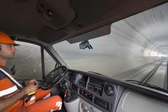 Ein Lokführer sitzt in einem Minibus auf einem Transportzug und bedient den Zug per Fernbedienung (Bild: Keystone)
