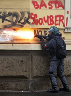 Ein italienischer Polizist feuert mit Tränengas auf die maskierten Demonstranten. (Bild: MASSIMO PERCOSSI)