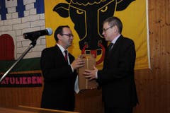 CVP-Ortspräsident Georges Danioth (links) überreicht dem neu gewählten Regierungsrat Urban Camenzind ein Geschenk. (Bild: Urs Hanhart / Neue UZ)