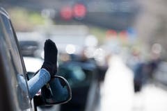 Der Osterverkehr staut sich auf der A2 Richtung Süden. In der Nähe von Silenen streckt eine Beifahrerin den Fuss aus dem geöffneten Autofenster. (Bild: KEYSTONE)