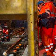 Arbeiter reiben mit einem goldigen Brett die Beton Schicht im längsten Eisenbahntunnel der Welt glatt. (Bild: SIGI TISCHLER)