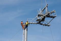 Ein Schwerlasthelikopter der Heliswiss liefert den Arbeitern am Mast die grossen vorfabrizierten Teile der Sesselbahn. (Bild: Keystone/Urs Flüeler)
