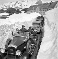 Eine Autokolonne zwischen den Schneemauern vor dem Hospiz auf dem Simplon bei der Wiedereröffnung der Simplonpassstrasse, aufgenommen an Pfingsten im Jahr 1937. (Bild: Keystone)