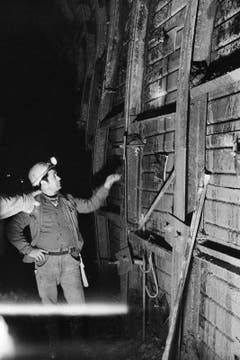 Tunnelarbeiter im Furkatunnel zeigen am 11. Dezember 1977 auf Seitenverstrebungen, die vom Felsdruck ins Innere des Tunnels gedrückt werden. Dies ist ein Grund für die Bauverzögerungen, die zur Folge hat, dass der Tunnel 80 Millionen Franken teurer wurde als geplant. (Bild: Keystone / Str)