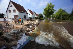 Hausbesitzer schützen sich mit Sandsäcken vor den Fluten. (Bild: Keystone)