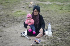 Die Regenfälle haben den Boden in Idomeni, auf welchem auch diese Frau und das Baby leben, in Schlamm verwandelt. (Bild: Keystone)