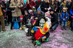 Eine als Hexe kostümierte Person und ein Kind liegen in den farbigen Konfetti am Boden umringt von Zuschauern. (Bild: ENNIO LEANZA)