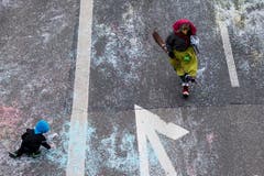 Eine als Hexe kostümierte Person läuft am Umzug "ZüriCarneval 2015", während ein Kind auf der Strasse mit Konfetti spielt. (Bild: ENNIO LEANZA)