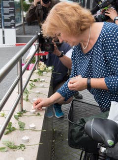 Eine Frau zündet eine kerze an. (Bild: AP/Sebastian Widmann)