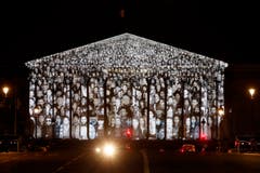 Der französische Künstler JR und der US-amerikanische Filmemacher Darren Aronofsky lassen Gesichter am französischen Parlamentsgebäude erstrahlen. (Bild: EPA / Yoan Valat)