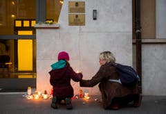 Eine Frau und ein Kind stellen eine Kerze vor die belgische Botschaft in Budapest. (Bild: Balazs Mohai/MTI via AP)