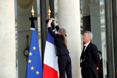 Eine Mitarbeiterin des Elysee-Palastes setzt die Fahnen auf halbmast. (Bild: EPA/Christophe Petit Tesson)