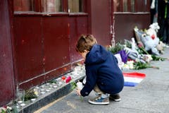 Ein kleiner Knabe legt vor dem Cafe Carillon in Paris Blumen nieder. (Bild: EPA/Yoan Valat)
