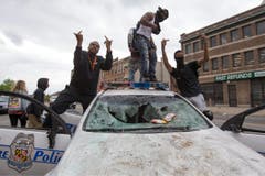 Jugendliche und ein zerstörtes Polizeifahrzeug. (Bild: EPA/ Michael Reynolds)