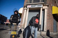 Szene nach den Unruhen: Ein Polizist hält Wache, ein Mann trägt den Abfall weg. (Bild: Keystone / EPA / John Taggart)